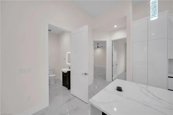Bathroom with marble finish floor, baseboards, toilet, and vanity