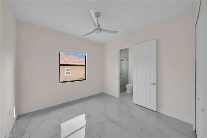Unfurnished bedroom featuring marble finish floor, connected bathroom, baseboards, and ceiling fan