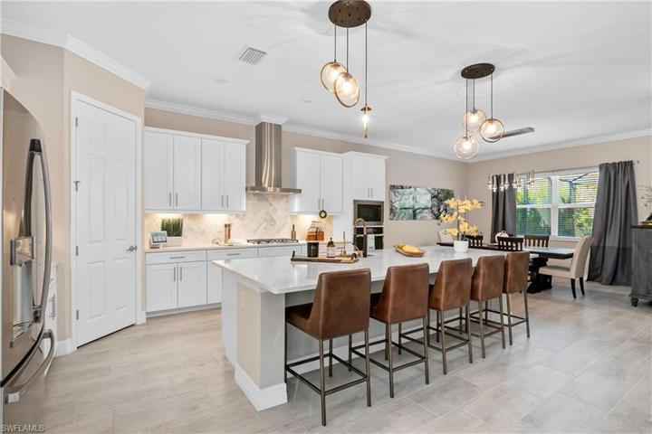 This kitchen offers plenty of space for entertaining guests with the oversize island, large dining space, upgraded appliances, and designer lighting.
