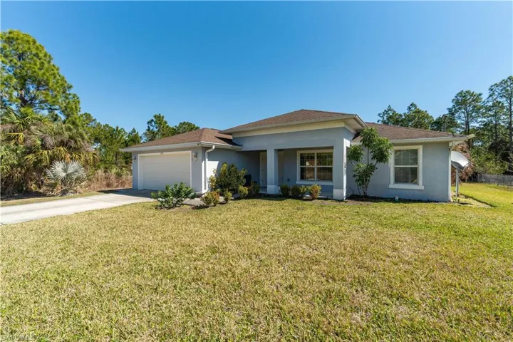 Single story home featuring stucco siding, a front yard, a garage, and concrete driveway