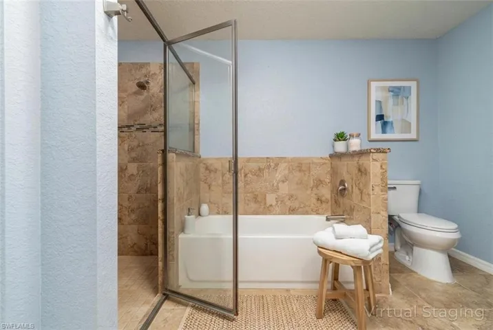 Bathroom featuring a bath, a shower stall, a textured ceiling, and a textured wall (Digitally Staged)