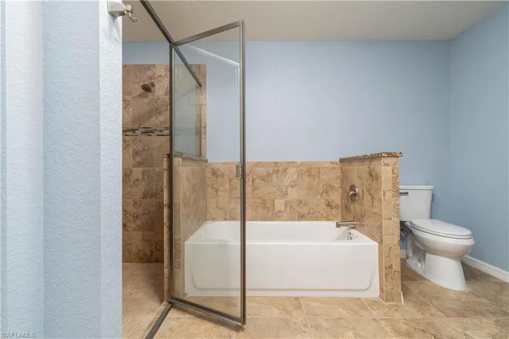 Bathroom featuring a garden tub, a stall shower, a textured ceiling, and a textured wall