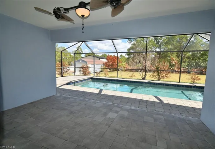 Swimming pool featuring a sunroom, a patio area, and glass enclosure
