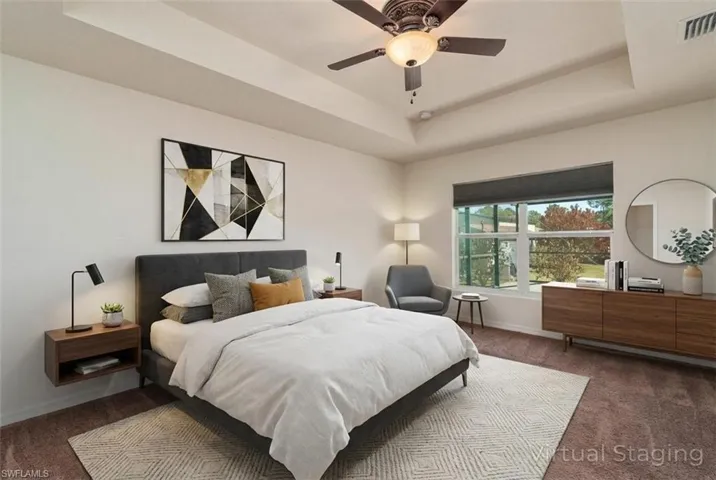 Carpeted bedroom featuring a raised ceiling and ceiling fan (Digitally Staged)