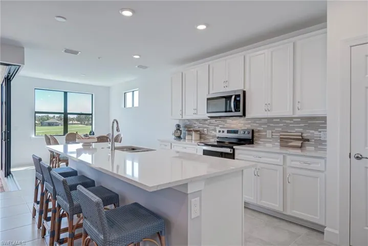 Kitchen with stainless steel appliances, white cabinetry, a kitchen snack bar, and recessed lighting