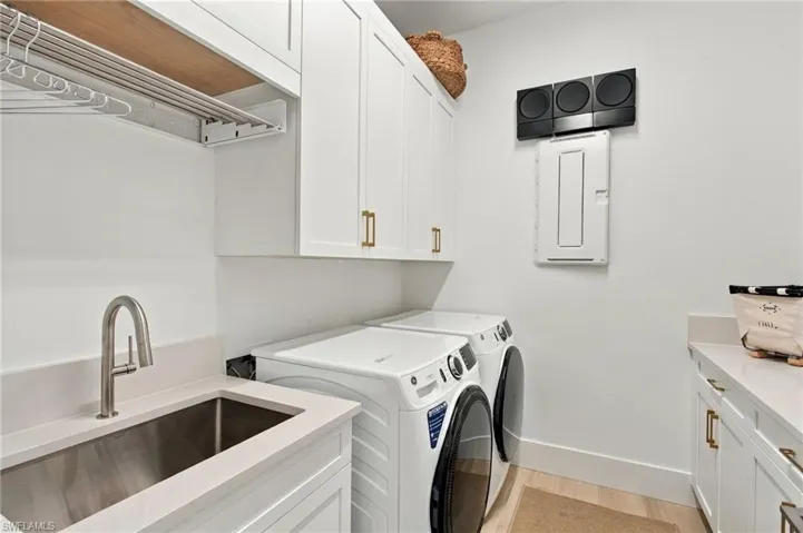 Room featuring custom built-in white cabinetry, integrated desk space, wood-finish flooring, recessed lighting, and a prominent gold-finish pendant light fixture
