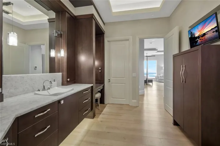 Primary bathroom with dual sinks, a separate vanity area and a large walk in closet.