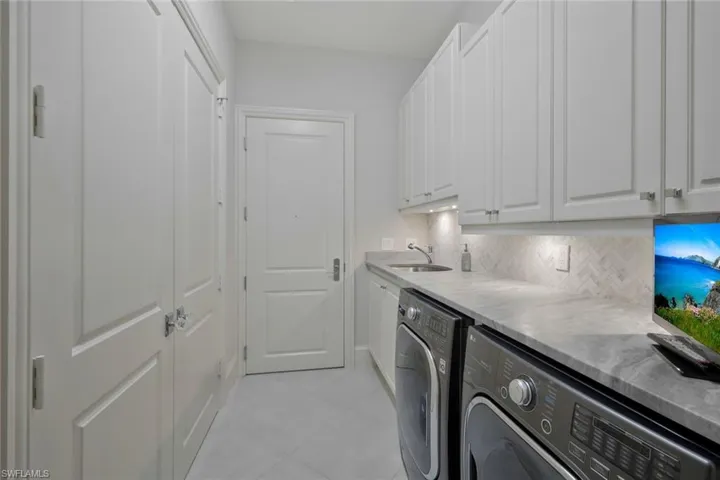 Laundry with storage and exit to hallway stair.