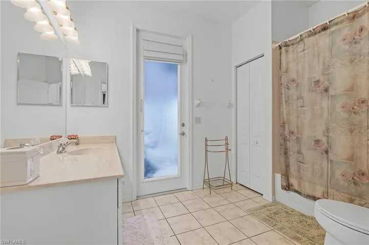 Full guest bathroom featuring toilet, shower / bath combo, vanity, and tile patterned floors with access to patio