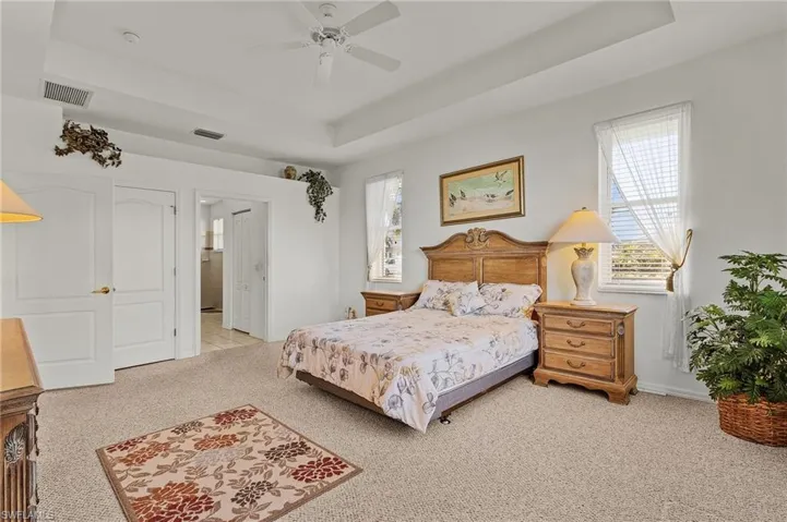 Carpeted bedroom featuring a tray ceiling and ceiling fan