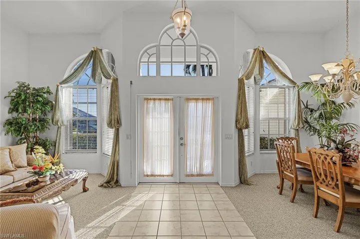 Foyer featuring light carpet, french doors, and a chandelier