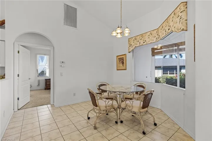 Breakfast area with a chandelier, light tile patterned floors, and high vaulted ceiling