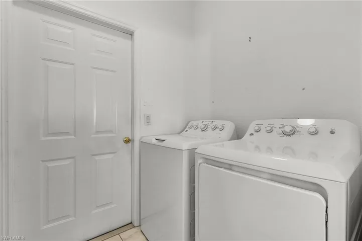 Clothes washing area with washer and dryer and light tile patterned floors