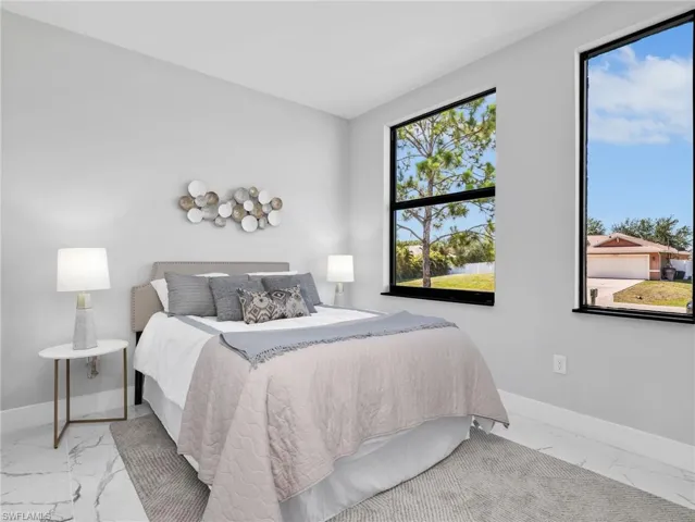 Brightly lit bedroom featuring large black-framed windows, light gray painted walls, and white marble-look tile flooring