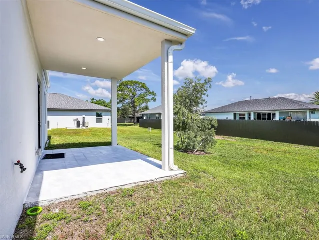 Expansive covered patio featuring recessed lighting, a tiled surface, and direct access to a large grass area