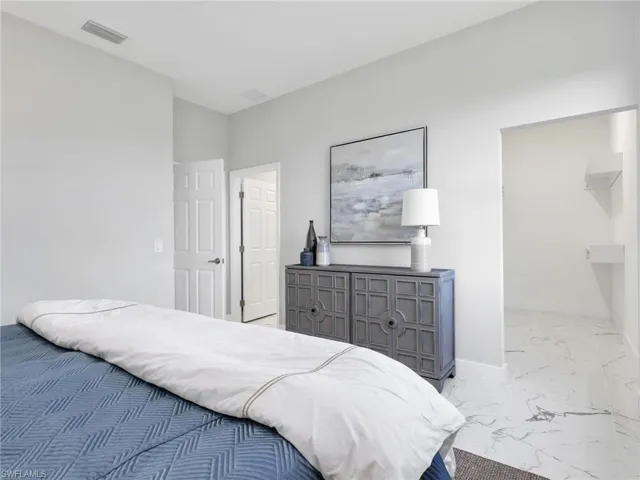 Bedroom featuring light gray wall tones, white trim, and a wide entryway