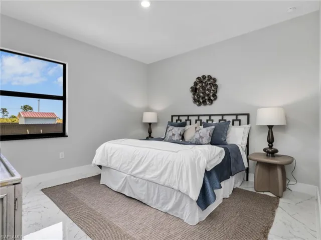 Spacious bedroom featuring light gray walls and large-format white tile flooring