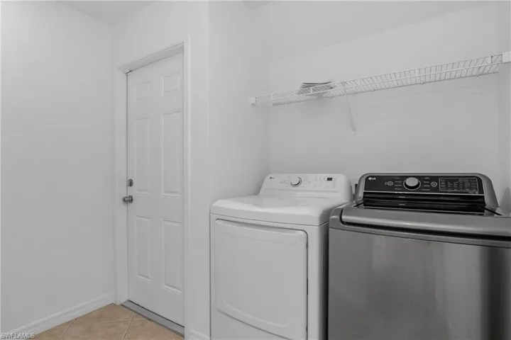Washroom featuring light tile patterned floors, baseboards, laundry area, and independent washer and dryer