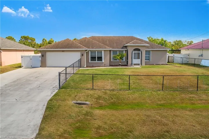 Ranch-style house with a gate, a garage, a front lawn, concrete driveway, and stucco siding