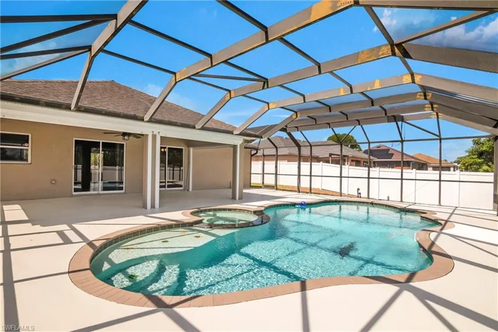 View of swimming pool featuring a lanai, ceiling fan, a patio area, and a pool with connected hot tub