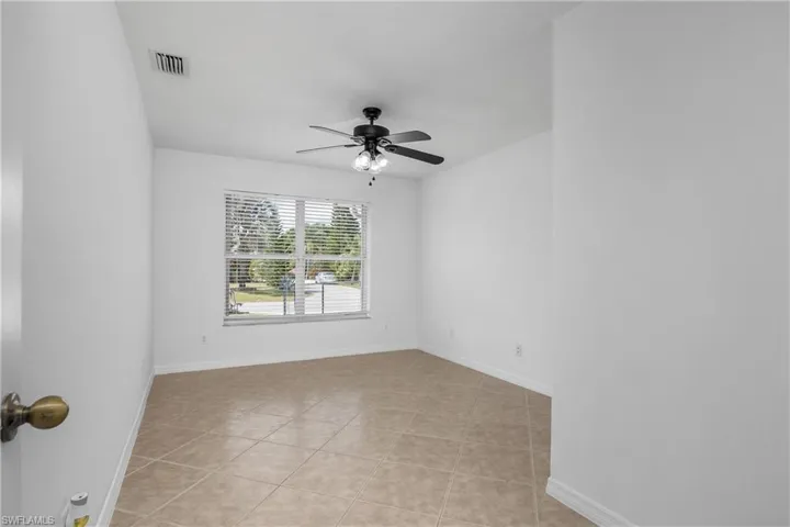 Spare room featuring baseboards, a ceiling fan, light tile patterned flooring, and visible vents