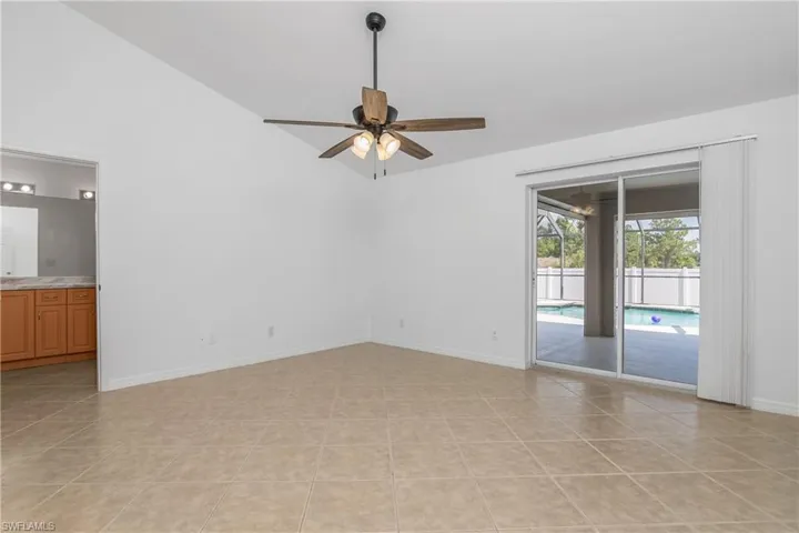 Unfurnished room with baseboards, a ceiling fan, light tile patterned floors, and lofted ceiling
