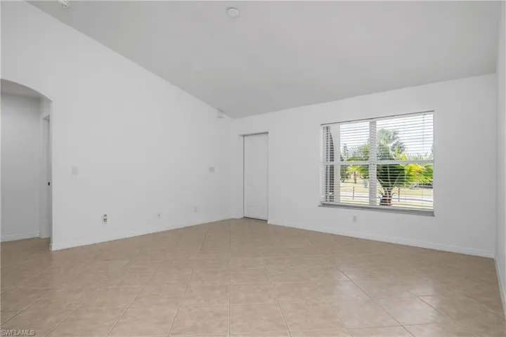 Unfurnished room with baseboards, arched walkways, light tile patterned floors, and high vaulted ceiling