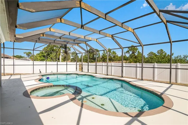 View of swimming pool featuring a pool with connected hot tub, fence, a lanai, and a patio area