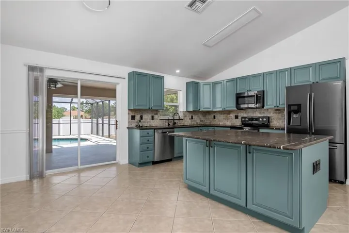 Kitchen with visible vents, decorative backsplash, a sink, appliances with stainless steel finishes, and vaulted ceiling