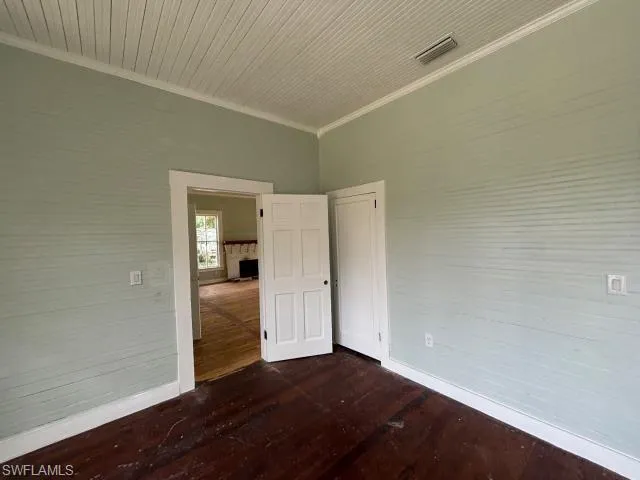 Spare room featuring ornamental molding and dark wood-style floors