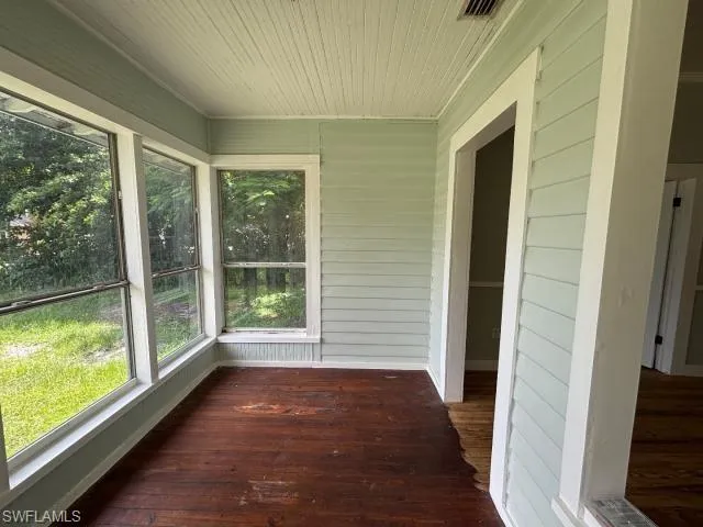 Unfurnished sunroom featuring wood ceiling, wooden walls, and hardwood / wood-style floors