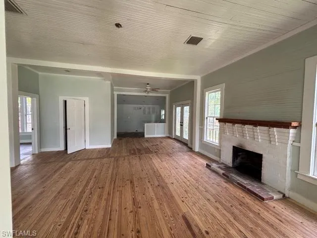 Unfurnished living room featuring a fireplace, healthy amount of natural light, hardwood / wood-style floors, and a ceiling fan