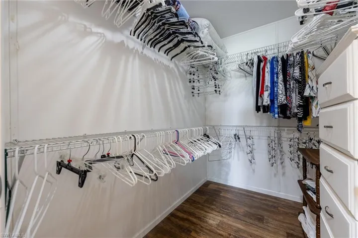Walk in closet with dark wood-type flooring