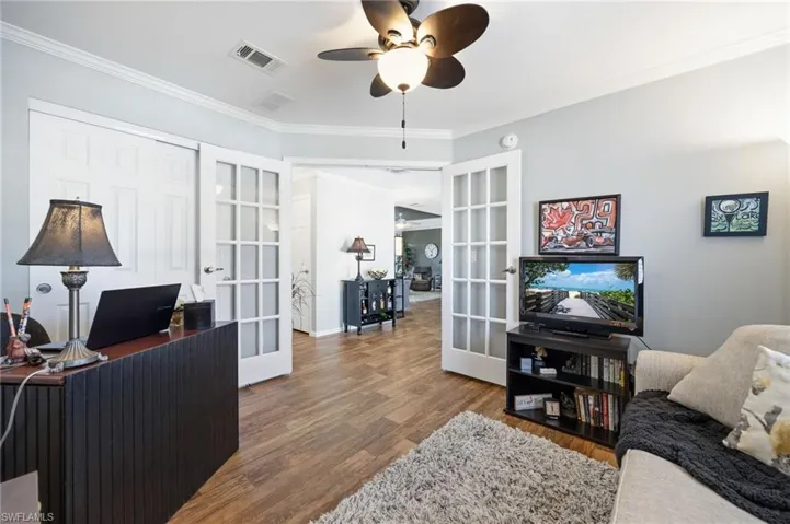 Home office featuring french doors, ornamental molding, ceiling fan, and dark wood finished floors