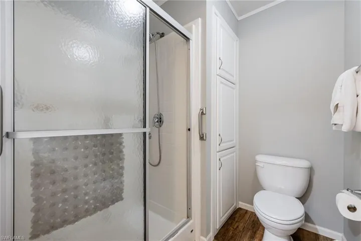 Full bath featuring a shower stall, a closet, and dark wood-style flooring