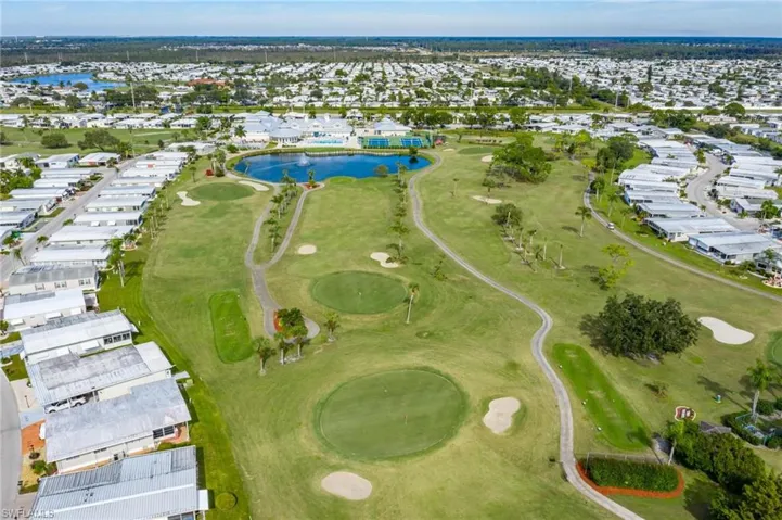 Aerial perspective of suburban area featuring a golf course and a nearby body of water