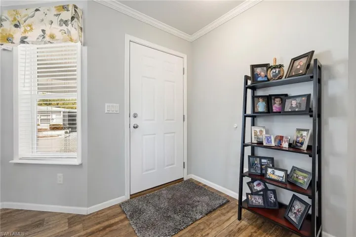 Entryway featuring crown molding and dark wood-style flooring