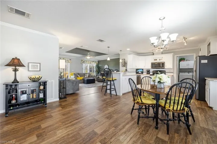 Dining area featuring ornamental molding, dark wood finished floors, washer / clothes dryer, and hanging lights