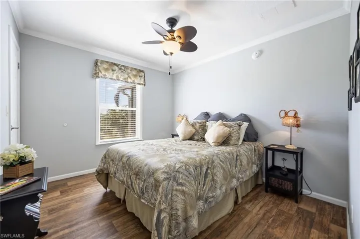 Bedroom featuring dark wood-style flooring, crown molding, and ceiling fan