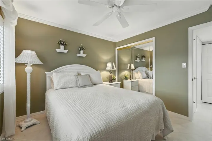Bedroom with ornamental molding, ceiling fan, tile patterned flooring, and a closet