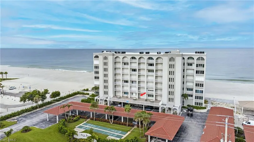 View of condo building / complex featuring view of water and beach