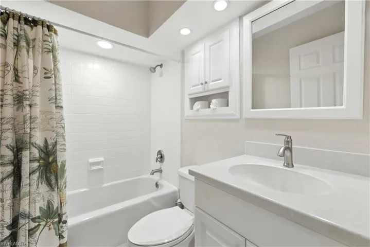 Bathroom with shower / bath combination with curtain, vanity, and recessed lighting