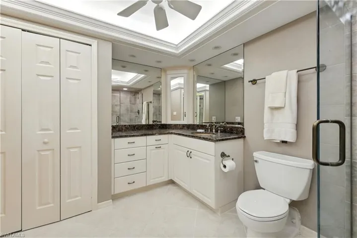 Bathroom with a closet, vanity, a stall shower, light tile patterned floors, and ornamental molding