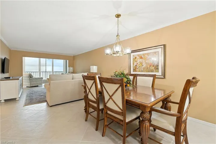 Dining space featuring crown molding, a chandelier, and light tile patterned flooring
