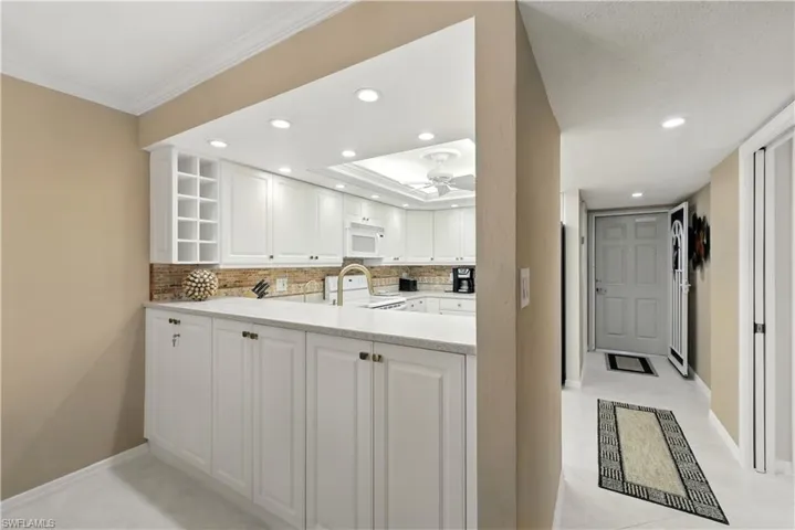 Kitchen featuring decorative backsplash, recessed lighting, white cabinetry, white appliances, and light stone counters