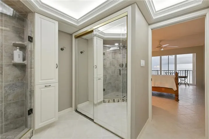 Full bath featuring a shower stall, light tile patterned floors, ceiling fan, and crown molding
