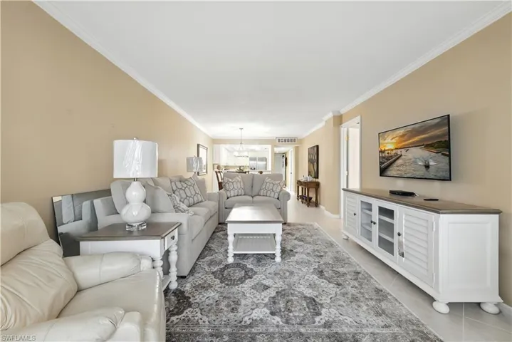 Living area with crown molding, light tile patterned floors, and a chandelier