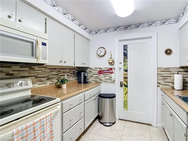 Kitchen featuring light-finish cabinetry with silver-tone hardware, durable countertops, and a full tile backsplash