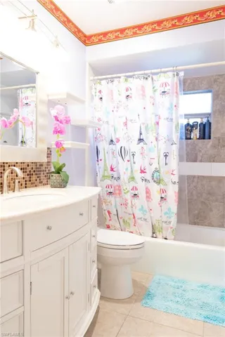 Full bathroom with vanity, shower / tub combo, light tile patterned flooring, and backsplash