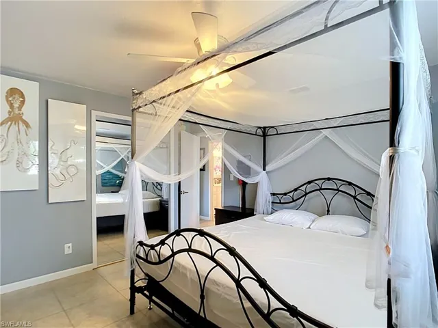 Bedroom featuring tile flooring, a ceiling fan, and mirrored closet doors